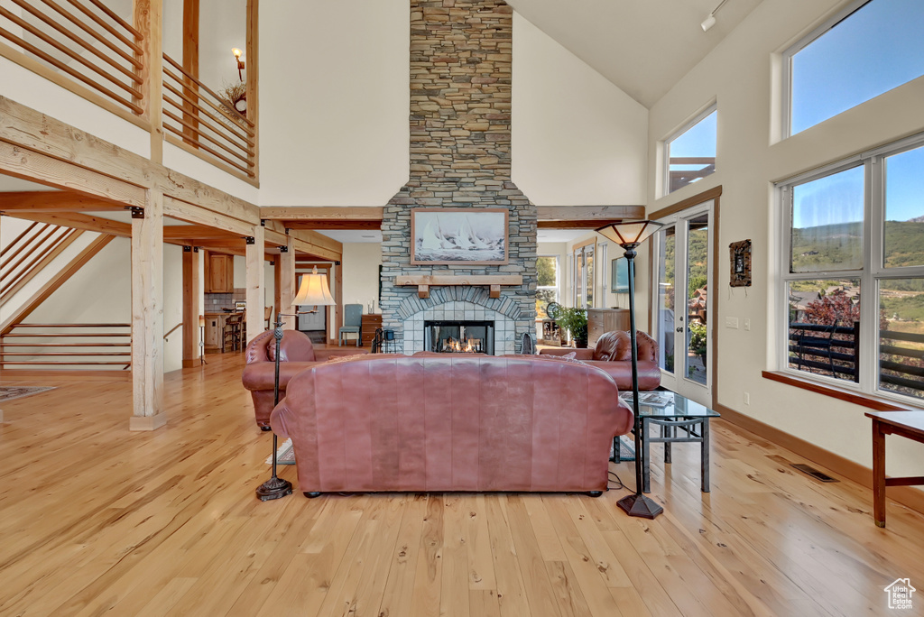Living room with a fireplace, high vaulted ceiling, and light wood-type flooring