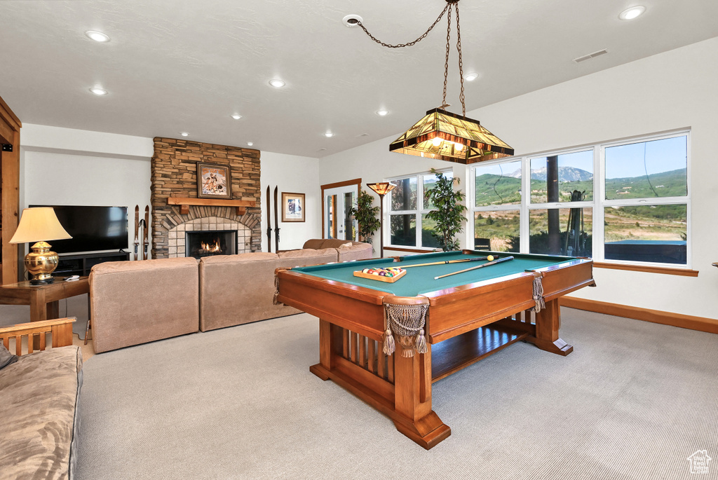 Game room with a stone fireplace, light colored carpet, and pool table