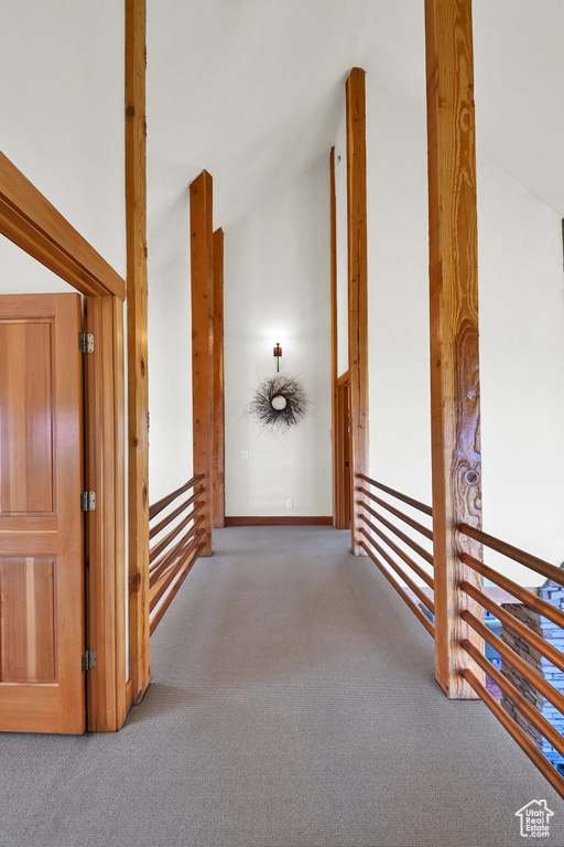 Hallway featuring lofted ceiling and dark colored carpet