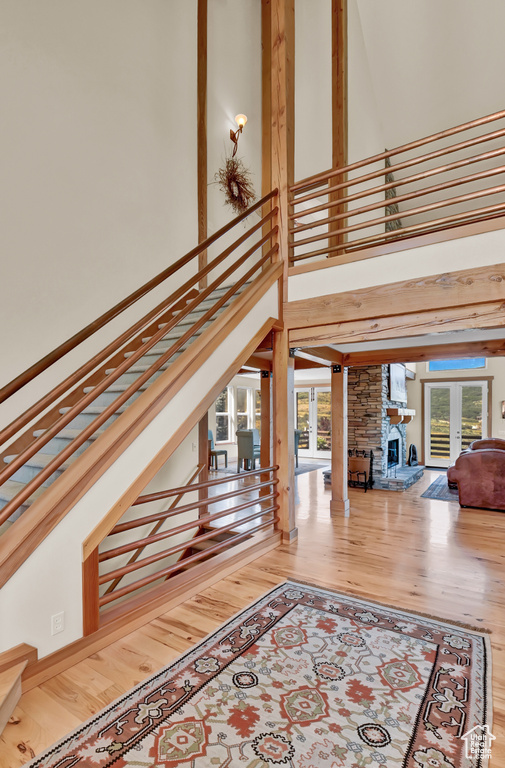 Stairway with light hardwood / wood-style floors, a high ceiling, and a fireplace