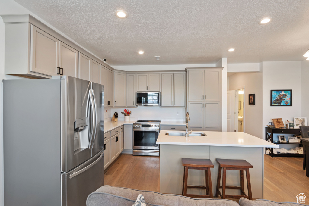 Kitchen featuring a breakfast bar area, appliances with stainless steel finishes, sink, and light wood-type flooring
