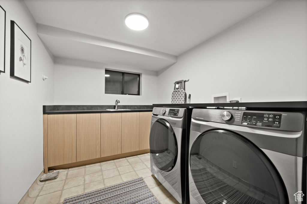Clothes washing area with independent washer and dryer, sink, and light tile flooring