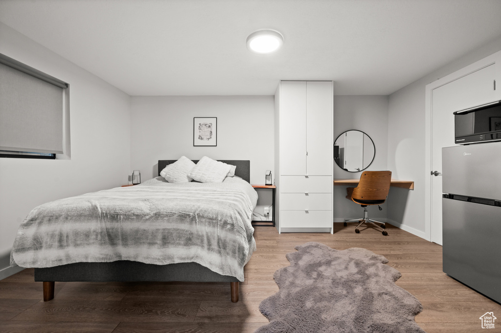Bedroom featuring light hardwood / wood-style floors and stainless steel refrigerator
