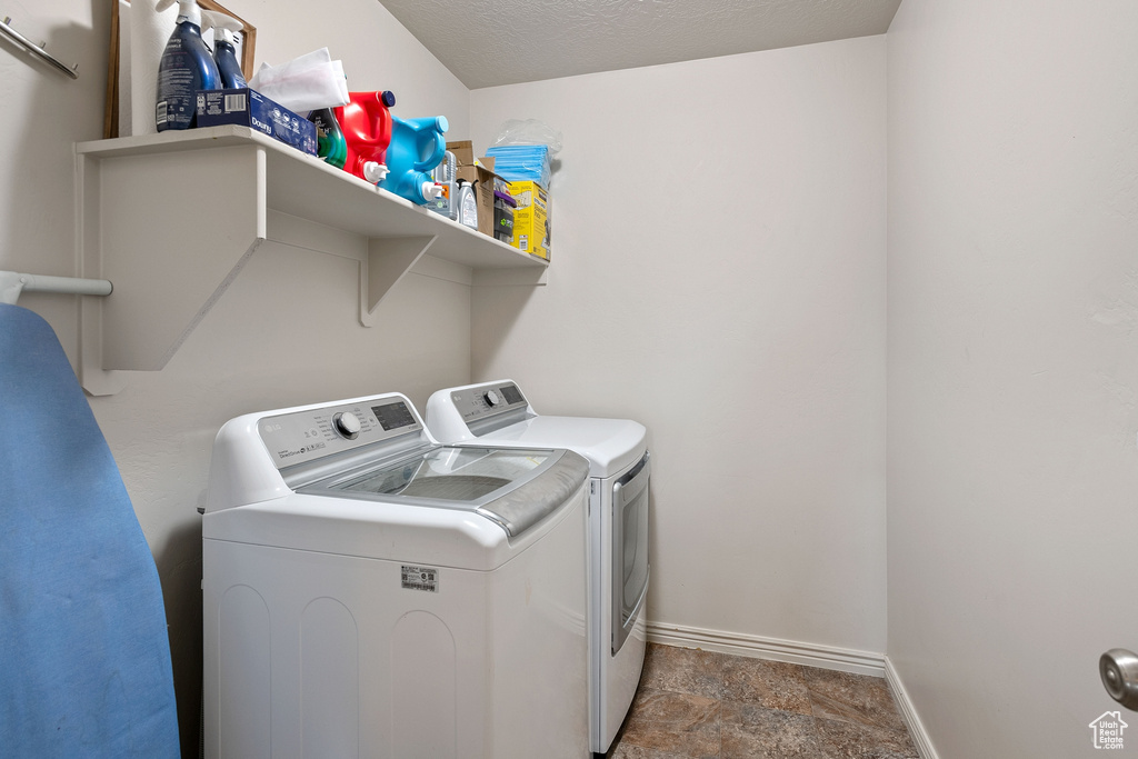 Laundry room featuring dark tile flooring and washer and clothes dryer