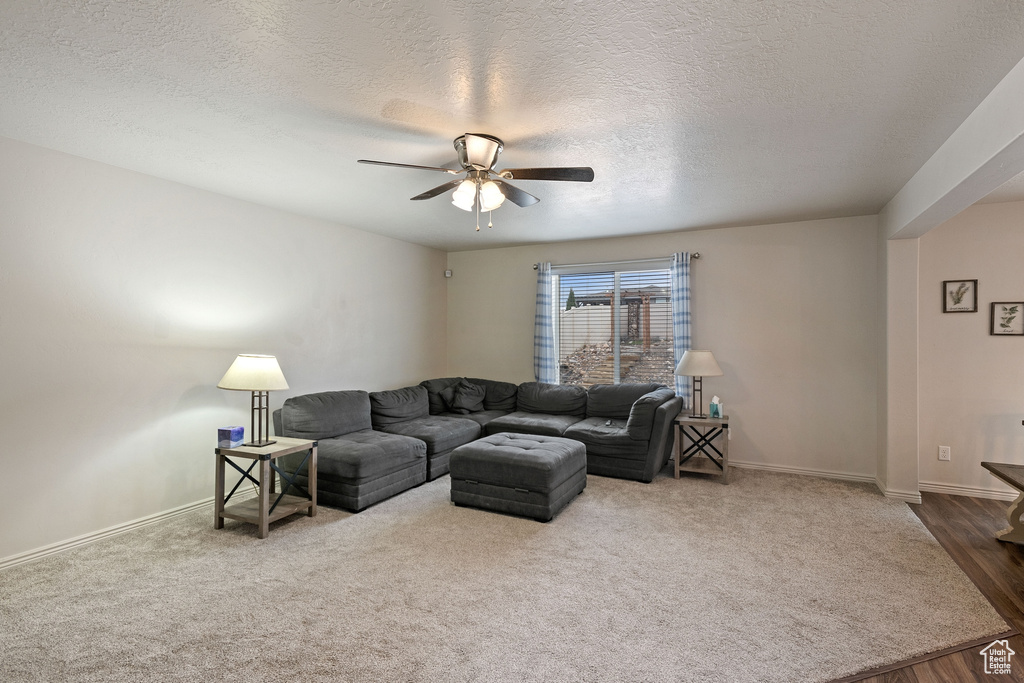 Living room featuring ceiling fan, carpet flooring, and a textured ceiling