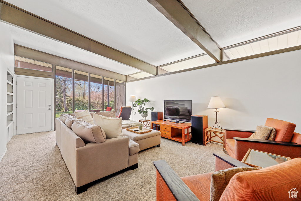 Carpeted living room featuring beam ceiling and a textured ceiling