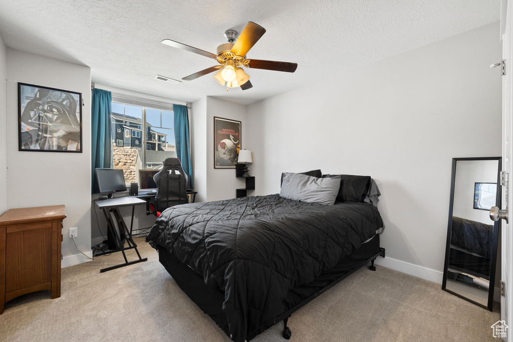 Bedroom with a textured ceiling, ceiling fan, and light carpet