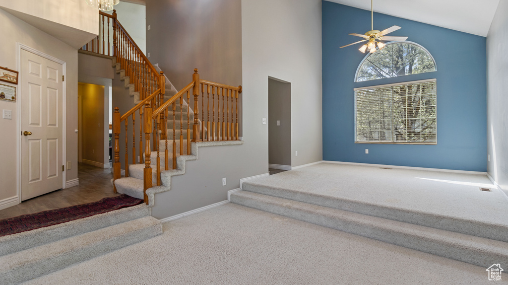 Carpeted entryway featuring ceiling fan and a high ceiling