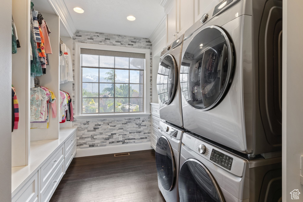 Laundry room with dark hardwood / wood-style floors, cabinets, and stacked washer / drying machine