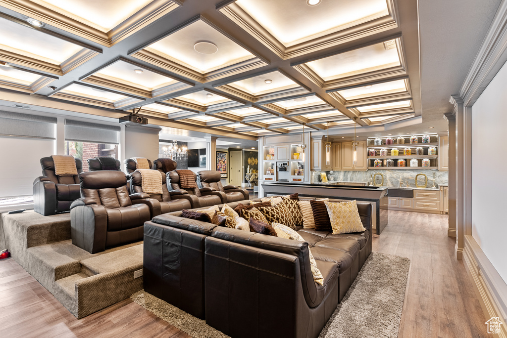 Cinema room featuring coffered ceiling, light hardwood / wood-style floors, and crown molding