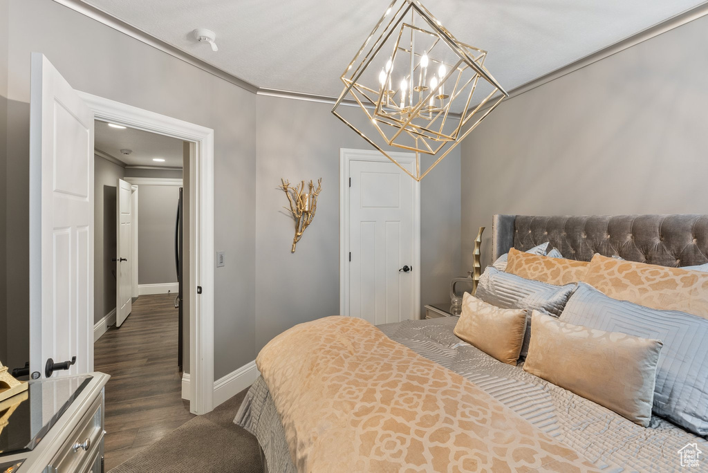Bedroom featuring dark hardwood / wood-style flooring, crown molding, and a notable chandelier