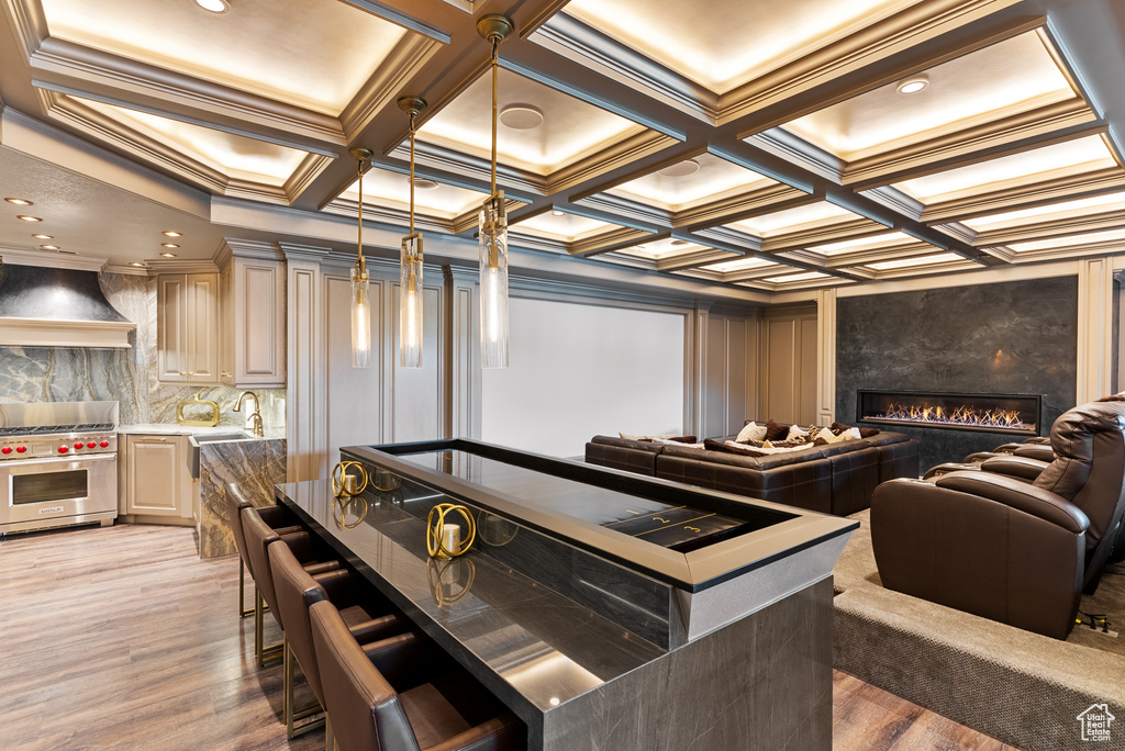 Interior space with decorative light fixtures, premium range hood, wood-type flooring, coffered ceiling, and luxury range