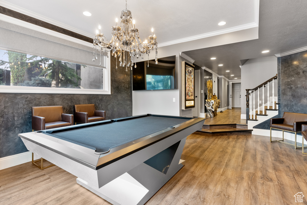 Rec room with pool table, crown molding, light wood-type flooring, and an inviting chandelier