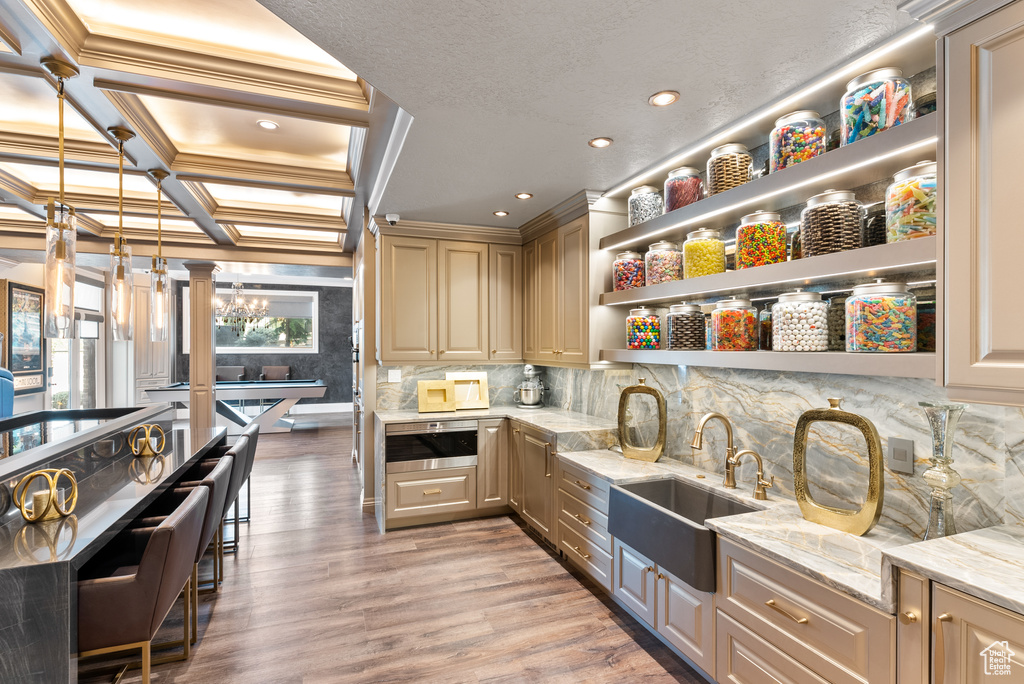 Kitchen featuring coffered ceiling, sink, backsplash, light hardwood / wood-style flooring, and light stone countertops