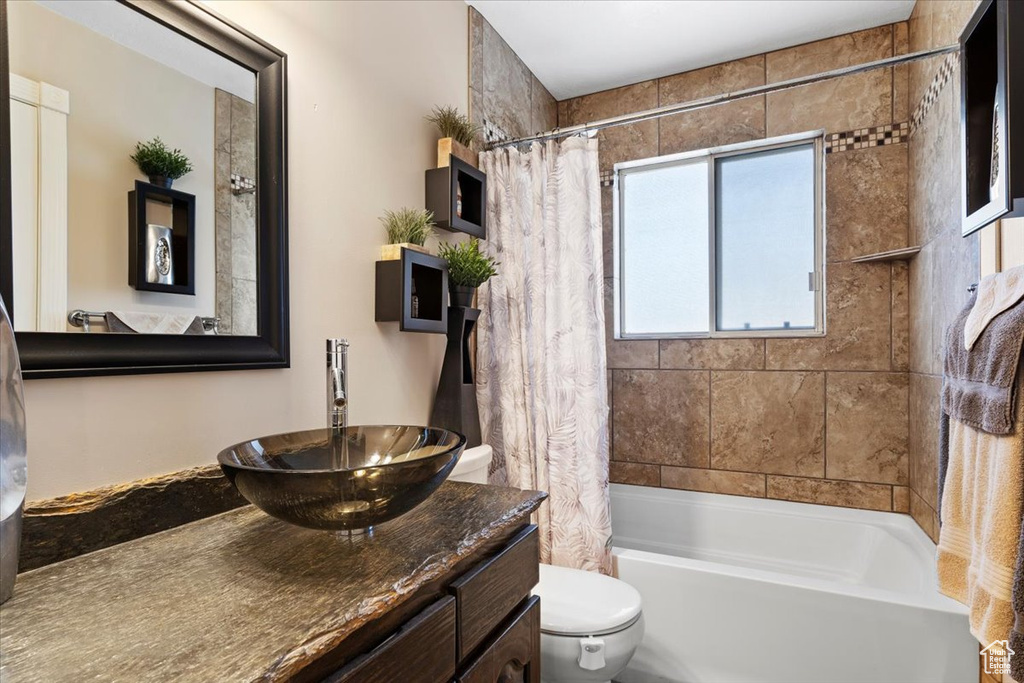 Full bathroom with vanity with extensive cabinet space, shower / bath combination with curtain, and toilet