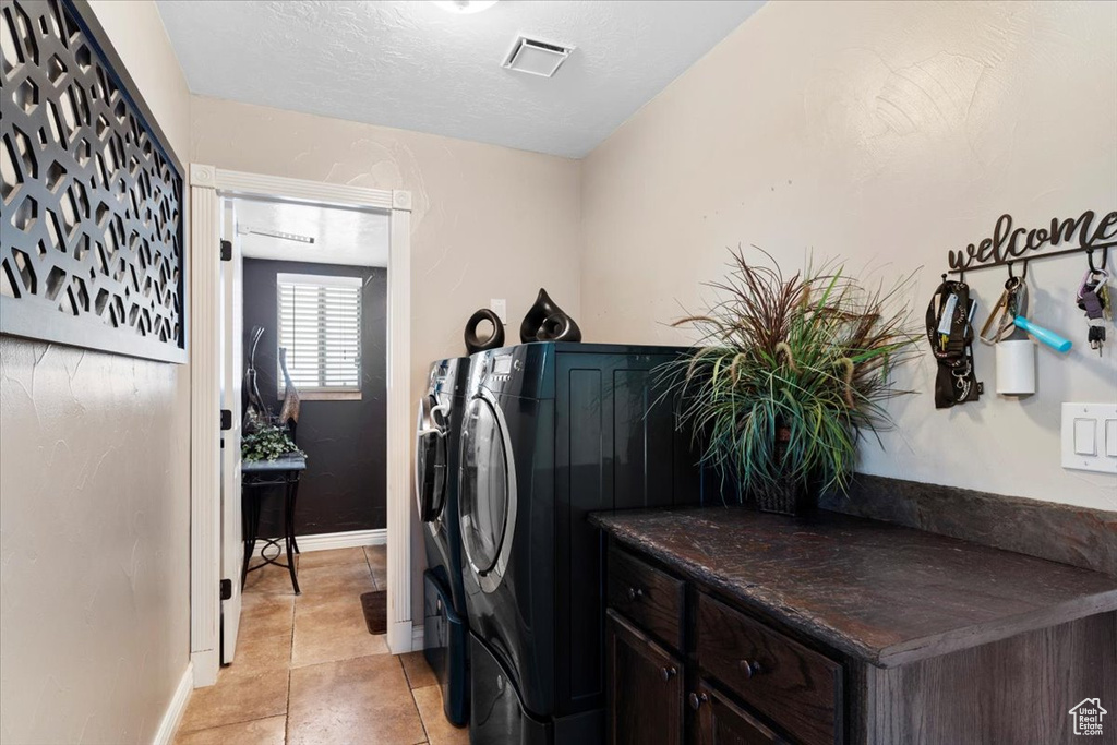 Laundry area with independent washer and dryer and light tile floors