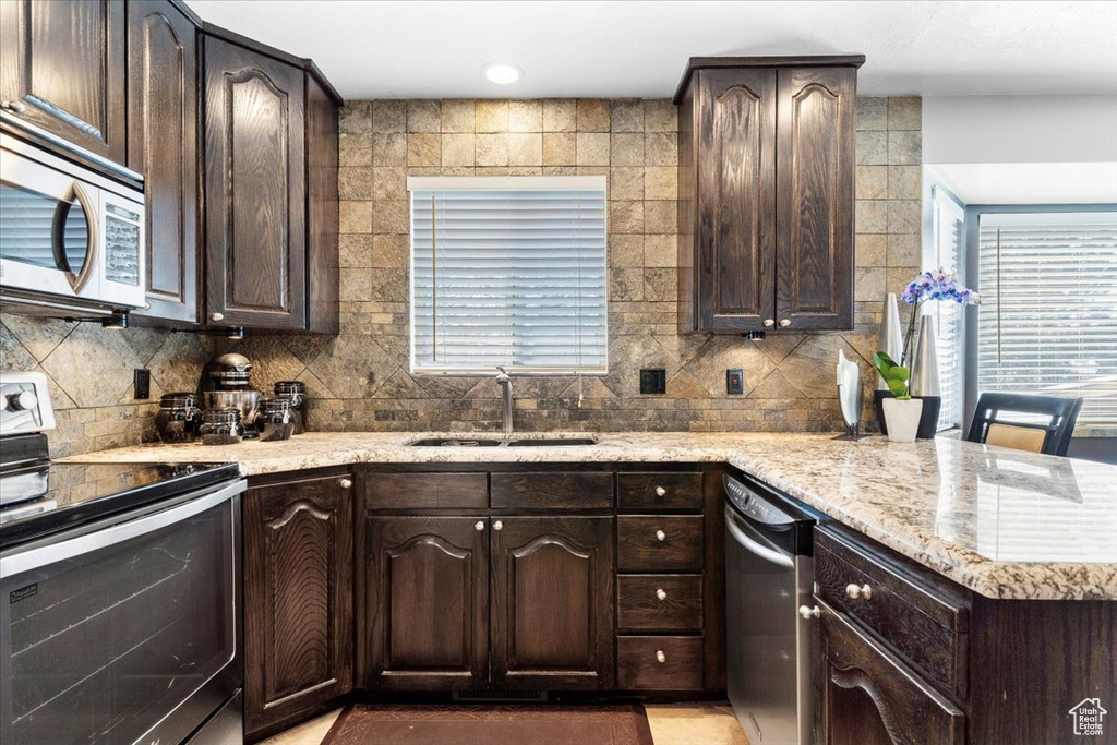 Kitchen featuring appliances with stainless steel finishes, dark brown cabinetry, and sink
