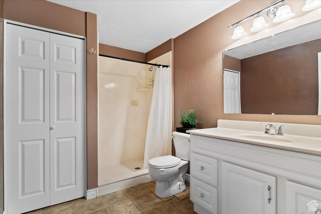 Bathroom featuring tile flooring, vanity with extensive cabinet space, toilet, and a shower with curtain