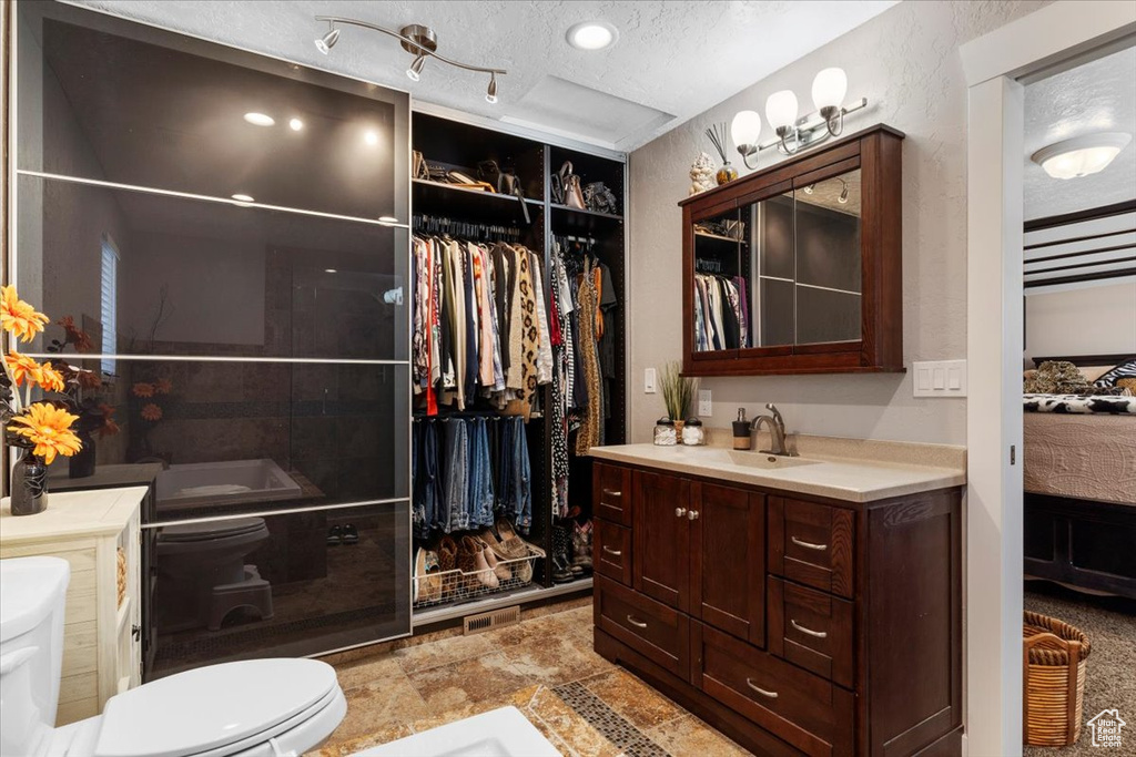 Bathroom featuring tile floors, toilet, large vanity, and a textured ceiling