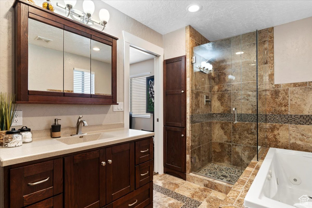 Bathroom featuring a textured ceiling, plus walk in shower, vanity, and tile flooring