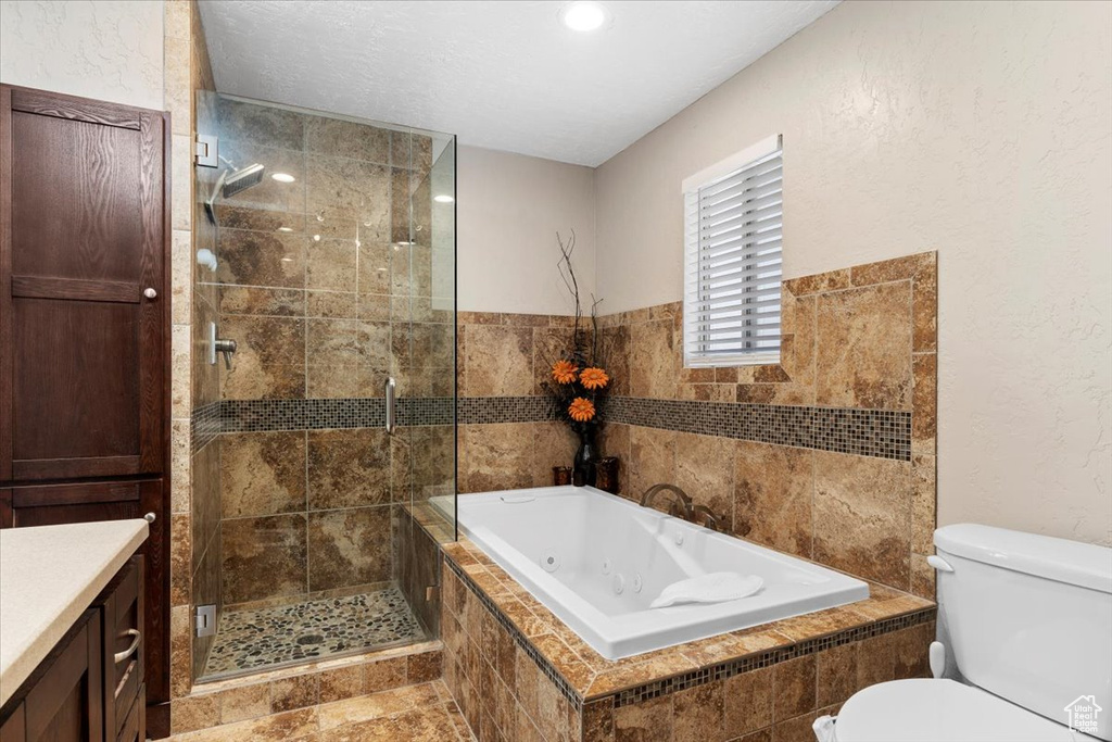 Full bathroom with vanity, toilet, tile flooring, and independent shower and bath