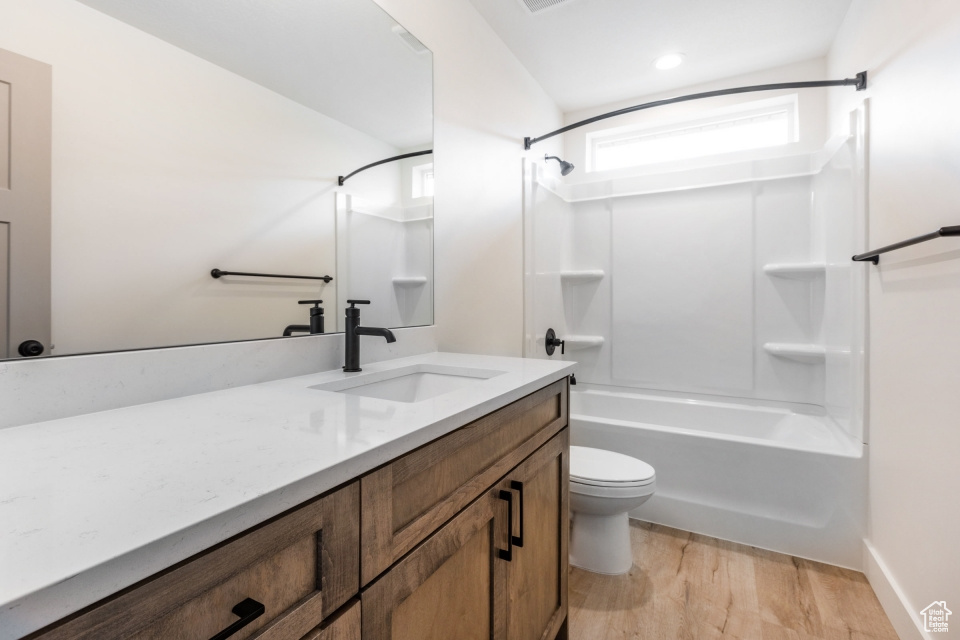 Full bathroom with vanity, toilet, hardwood / wood-style flooring, and  shower combination