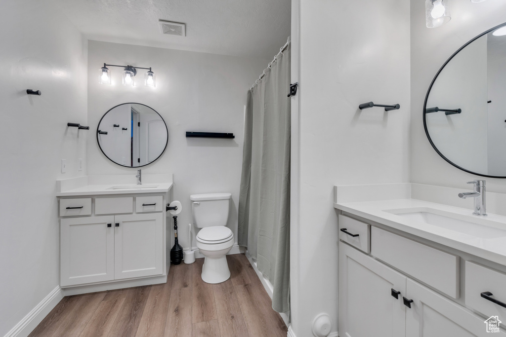 Bathroom featuring dual sinks, hardwood / wood-style flooring, toilet, and large vanity