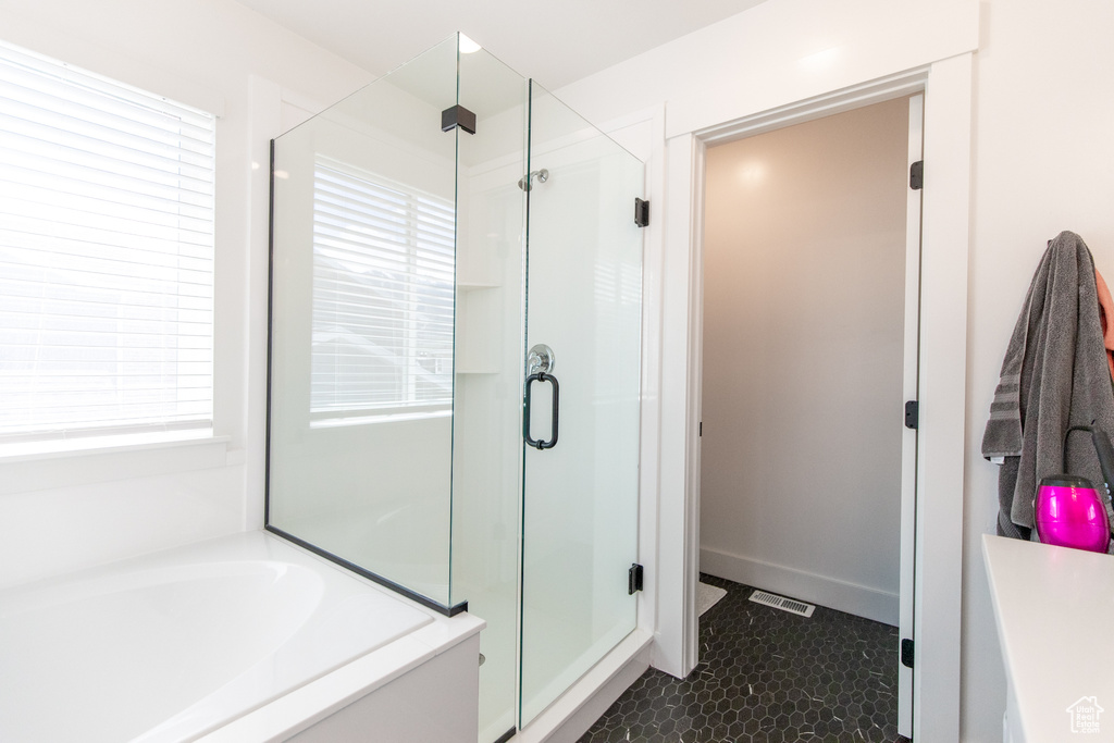 Bathroom featuring a wealth of natural light, separate shower and tub, and tile flooring