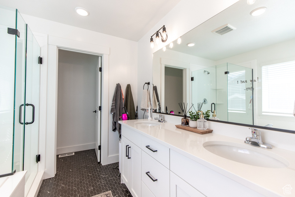 Bathroom featuring dual sinks, oversized vanity, an enclosed shower, and tile floors