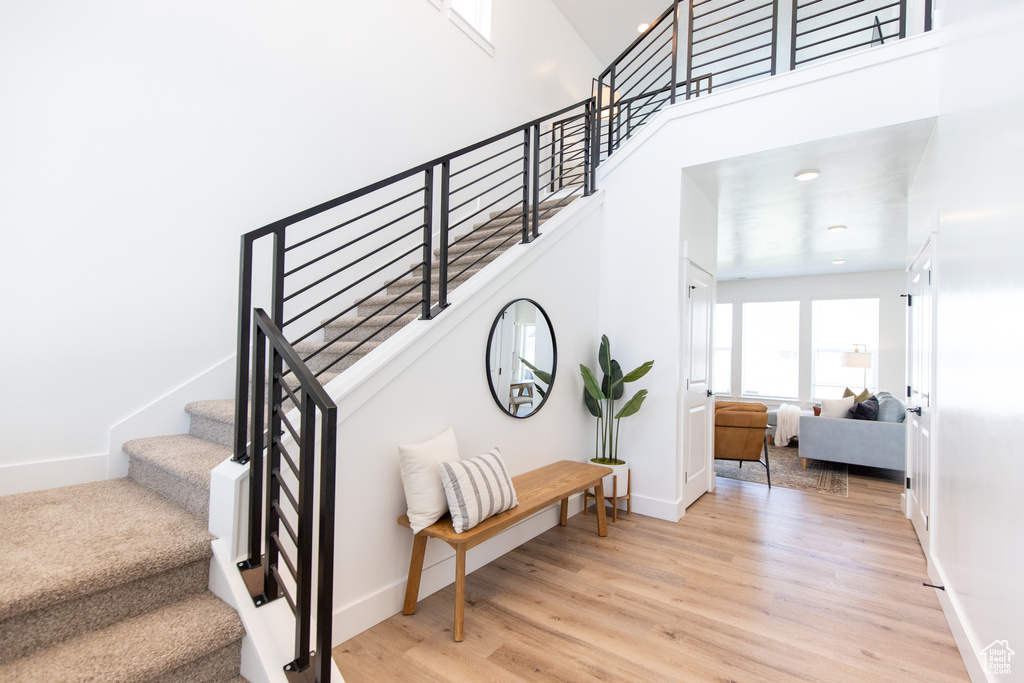 Staircase featuring a towering ceiling and light hardwood / wood-style floors