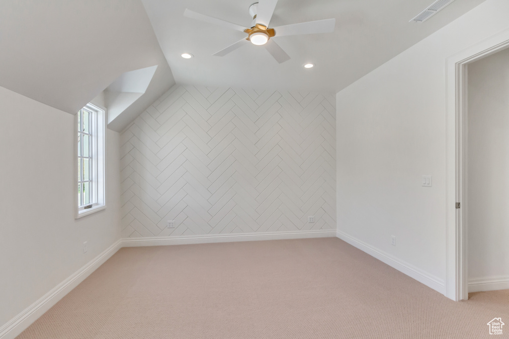 Additional living space with light carpet, ceiling fan, and vaulted ceiling