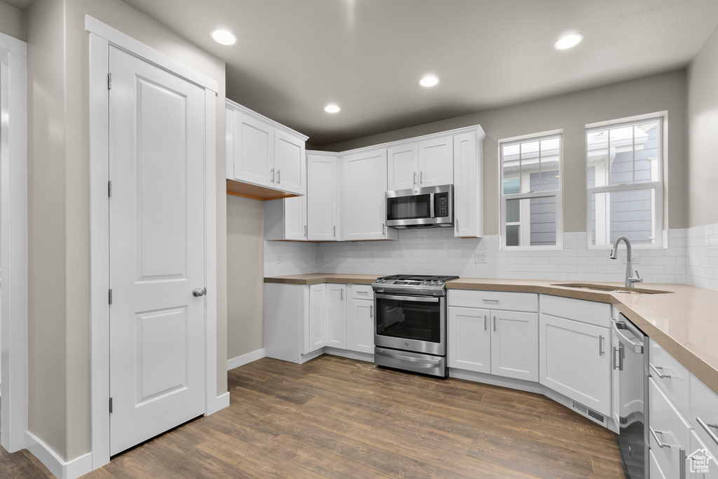 Kitchen featuring tasteful backsplash, dark hardwood / wood-style flooring, stainless steel appliances, and white cabinets