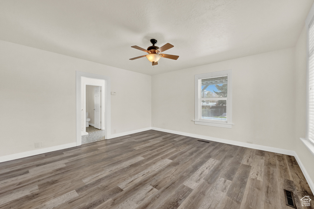 Empty room with ceiling fan and dark hardwood / wood-style floors