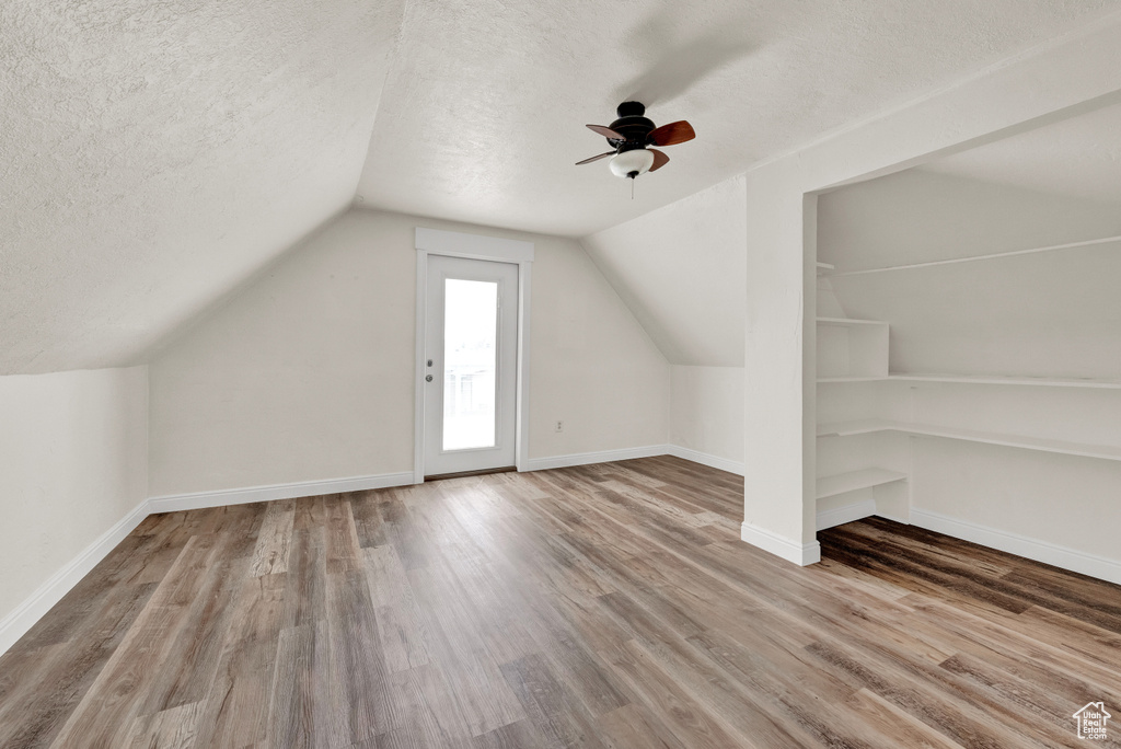Bonus room with vaulted ceiling, wood-type flooring, ceiling fan, and a textured ceiling