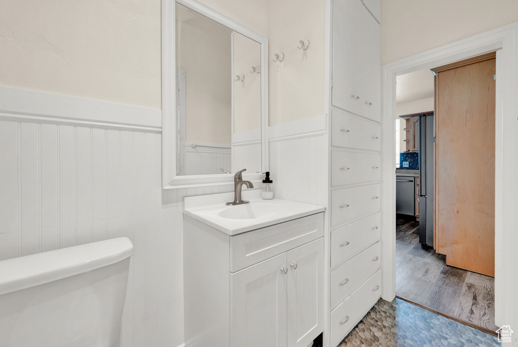 Bathroom featuring vanity with extensive cabinet space, hardwood / wood-style flooring, and toilet