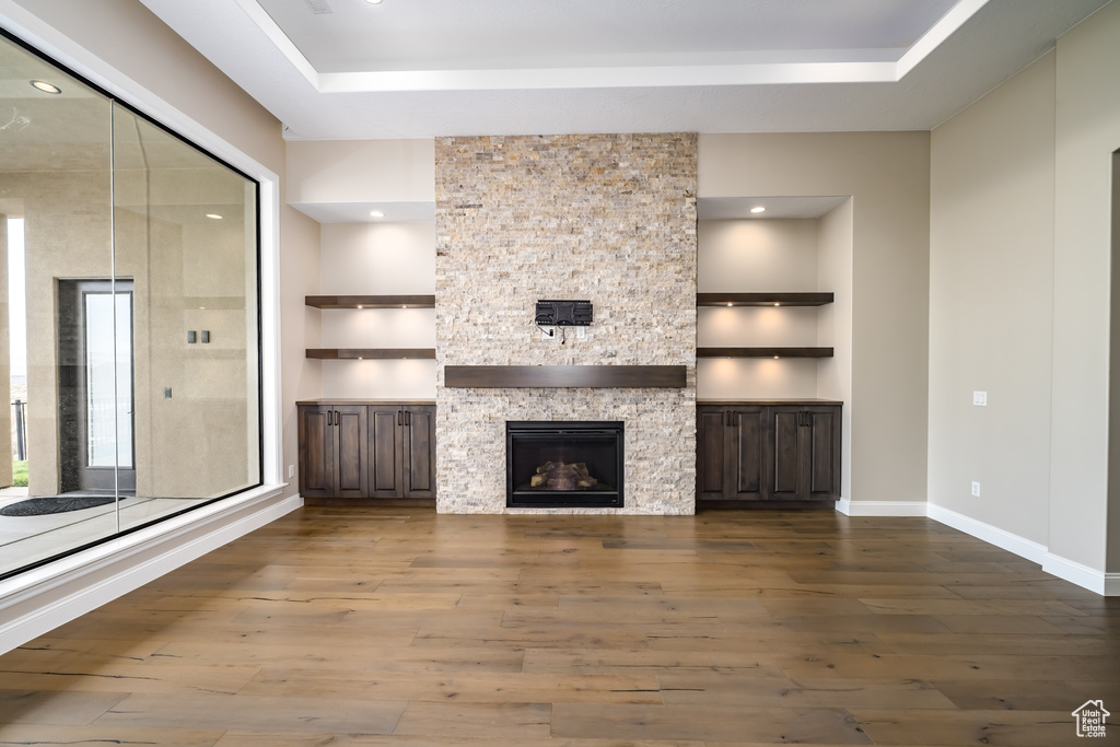 Unfurnished living room with a raised ceiling, hardwood / wood-style floors, and a fireplace