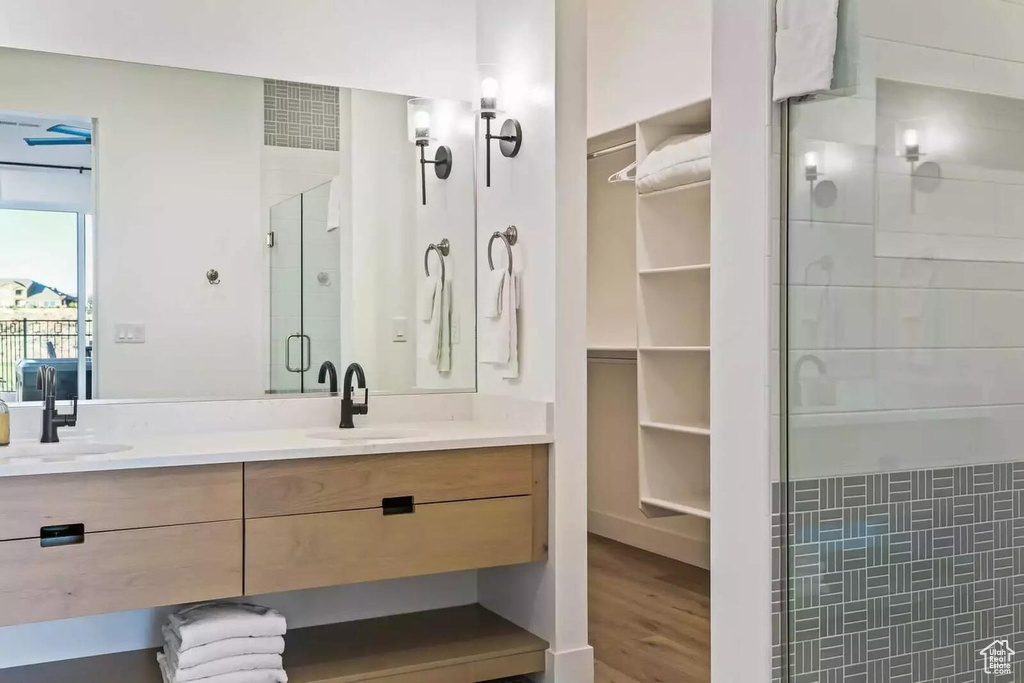 Bathroom with tile walls, large vanity, double sink, hardwood / wood-style floors, and walk in shower
