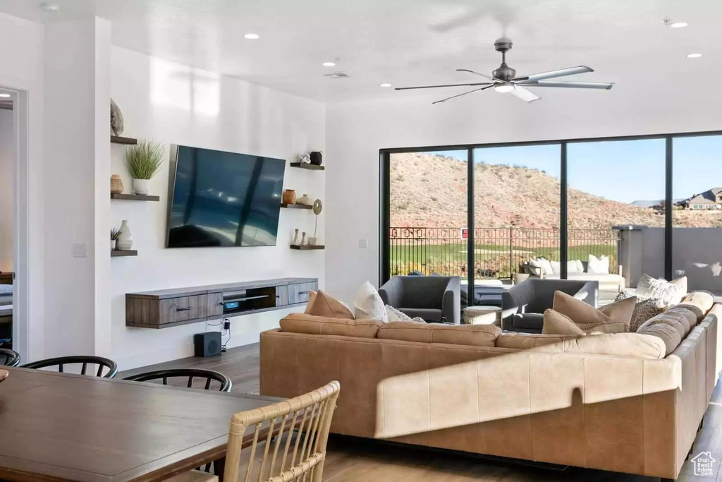 Living room with a mountain view, a healthy amount of sunlight, ceiling fan, and hardwood / wood-style floors