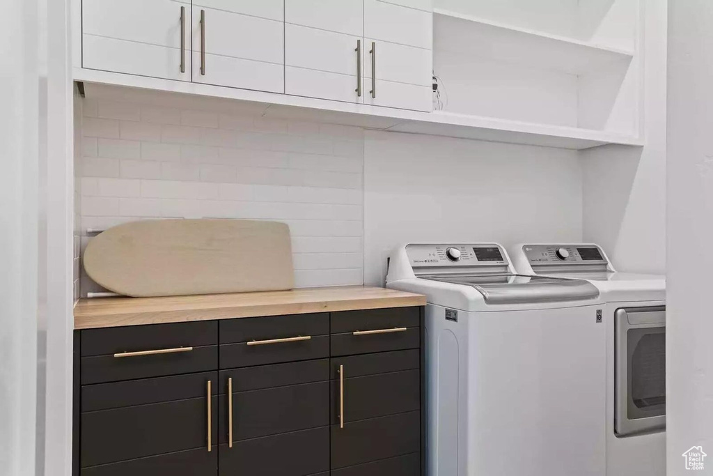Washroom featuring independent washer and dryer and cabinets