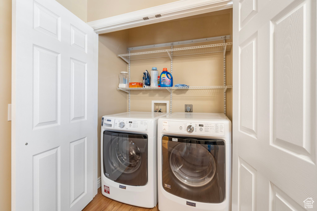 Laundry area with electric dryer hookup, washer hookup, light hardwood / wood-style flooring, and washing machine and dryer