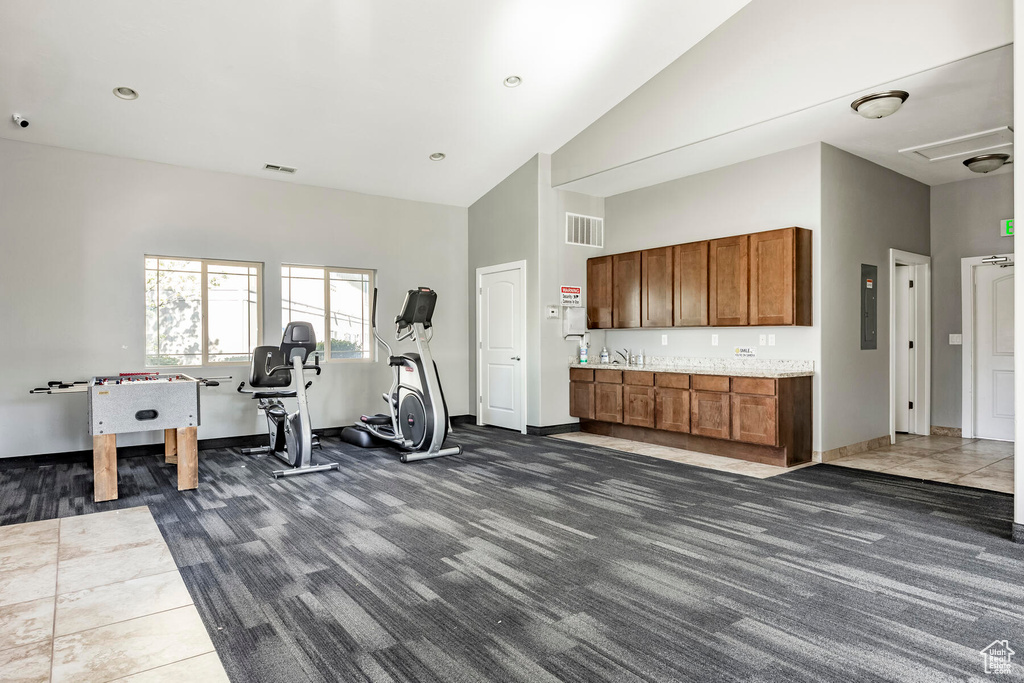 Workout area with dark tile flooring and high vaulted ceiling