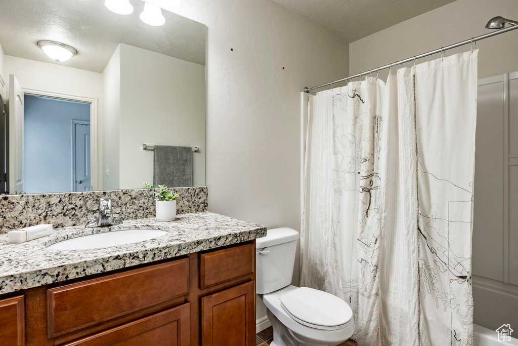 Full bathroom with toilet, shower / bath combination with curtain, and large vanity