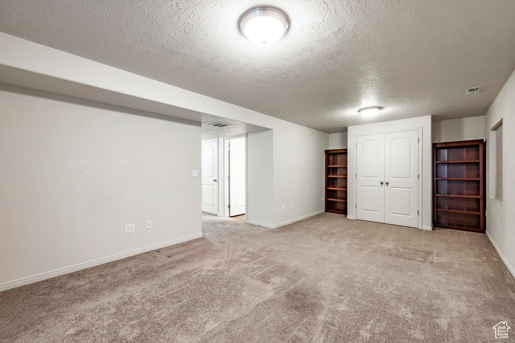 Basement featuring a textured ceiling and light carpet