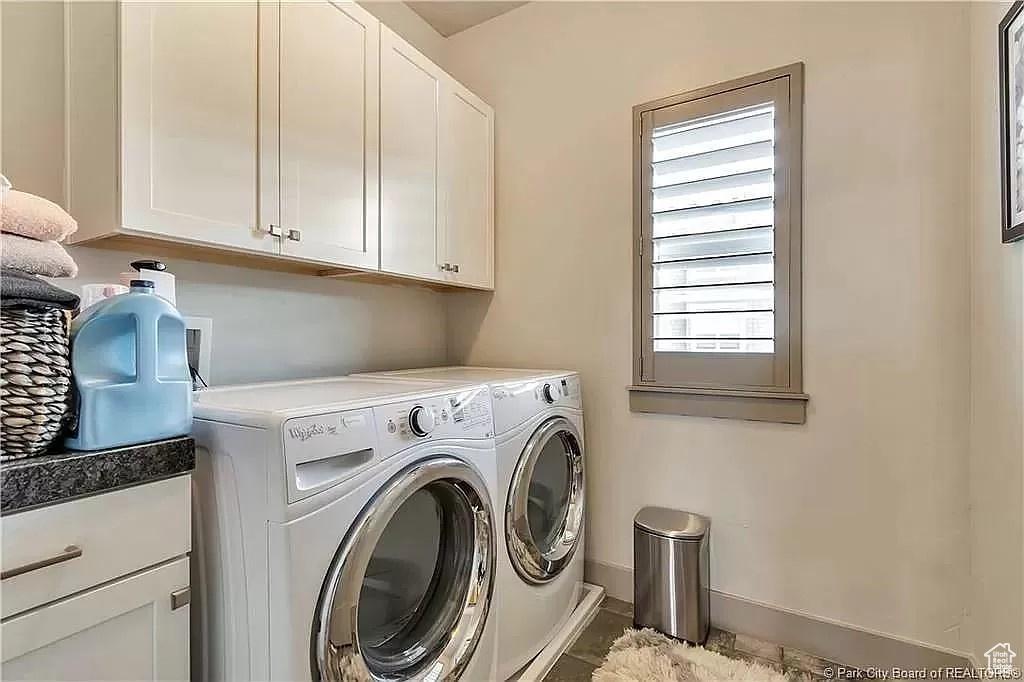 Laundry room featuring washer and clothes dryer, tile floors, and cabinets