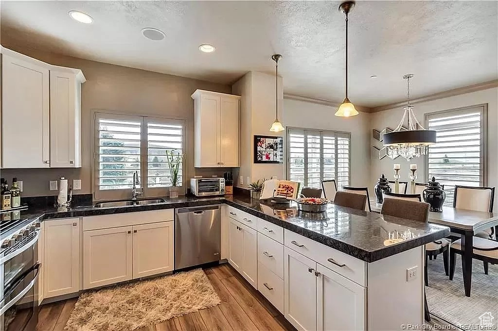 Kitchen featuring a wealth of natural light, appliances with stainless steel finishes, decorative light fixtures, and light wood-type flooring