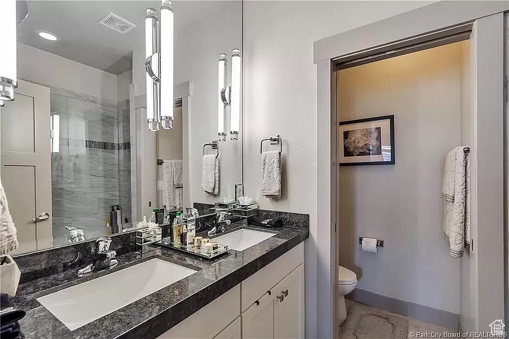 Bathroom with walk in shower, toilet, tile floors, and dual vanity
