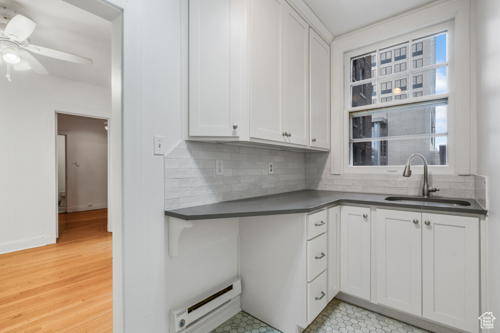 Kitchen featuring backsplash, light hardwood / wood-style flooring, ceiling fan, white cabinets, and sink