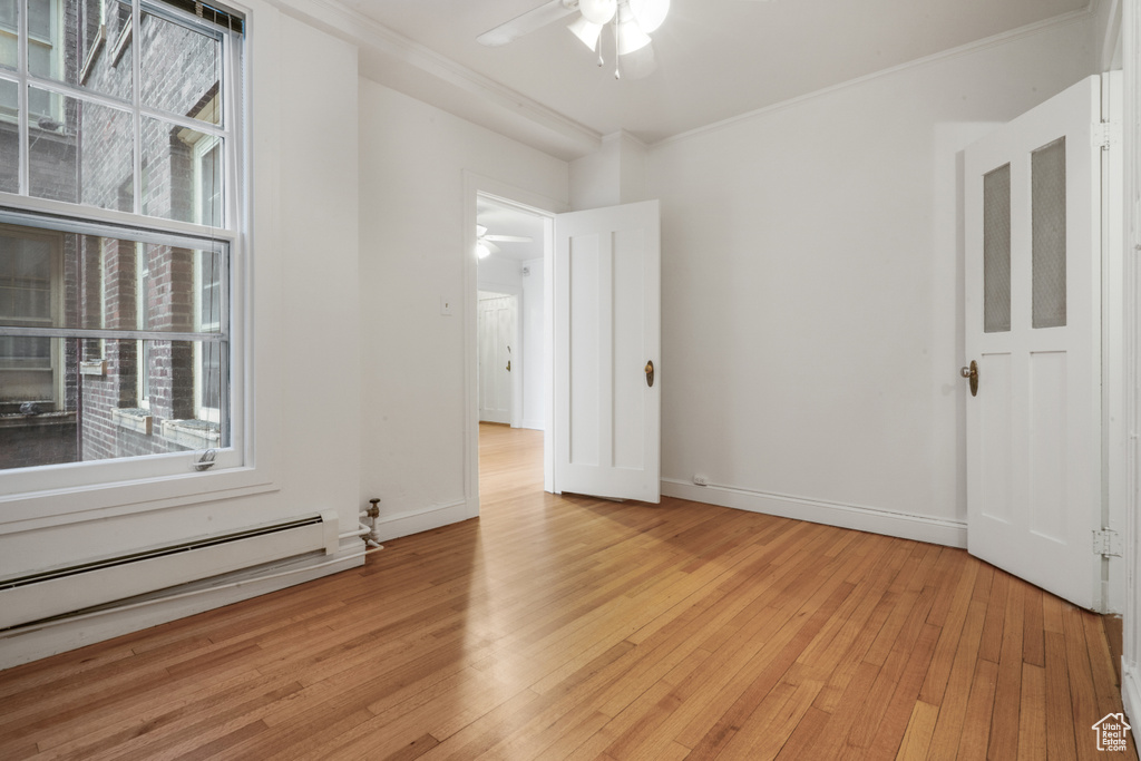 Spare room featuring light hardwood / wood-style flooring, ceiling fan, and baseboard heating