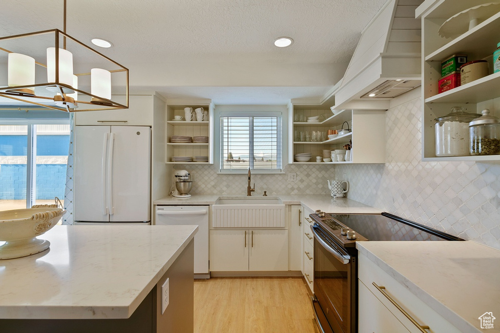 Kitchen featuring backsplash, light hardwood / wood-style flooring, white appliances, and light stone countertops