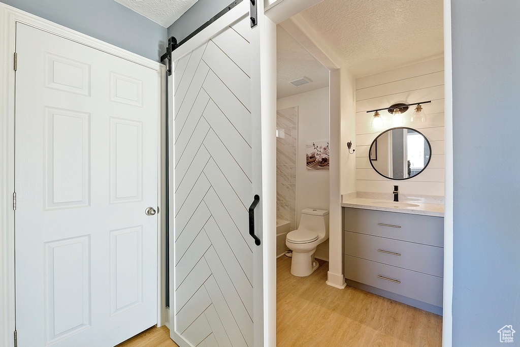Bathroom with vanity with extensive cabinet space, a textured ceiling, toilet, and hardwood / wood-style floors